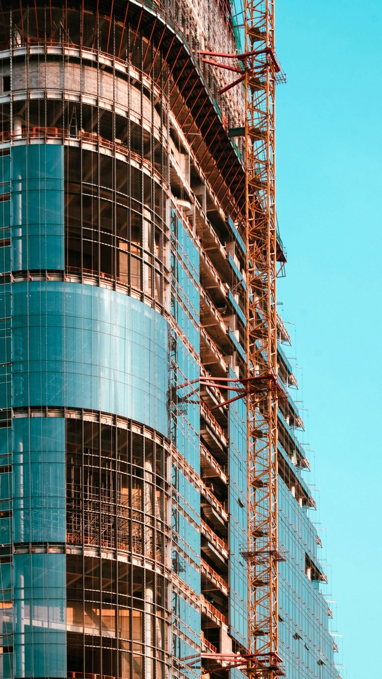 Glass-clad high-rise under construction with a tower crane