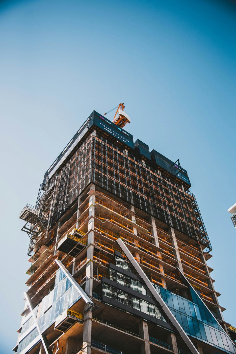 Tower under construction with a crane on the roof, seen from below